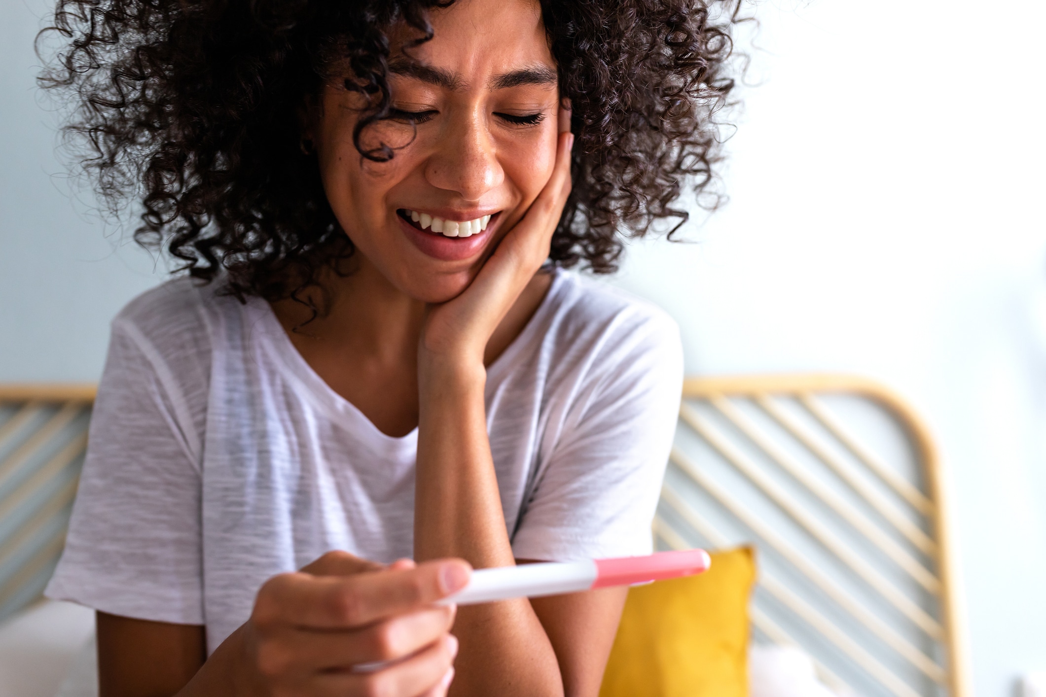 Glückliche afrikanische Frau hält einen positiven Schwangerschaftstest in der Hand